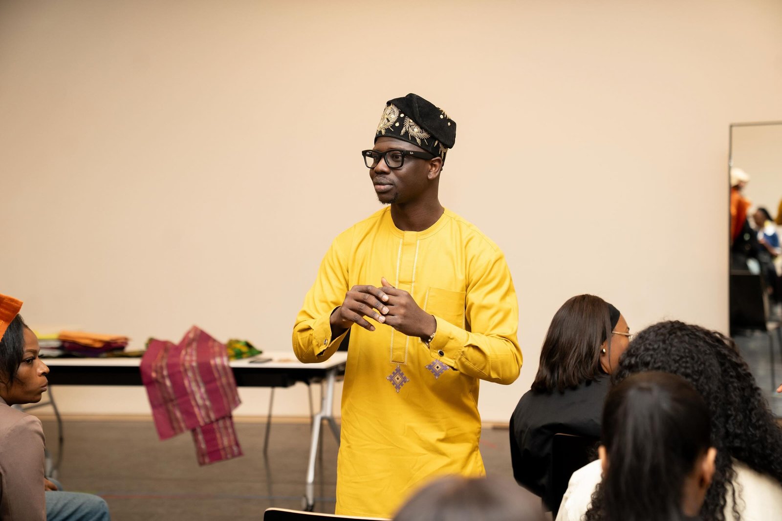 Jaaythecreator speaking to a group, fabric samples on the table beside him